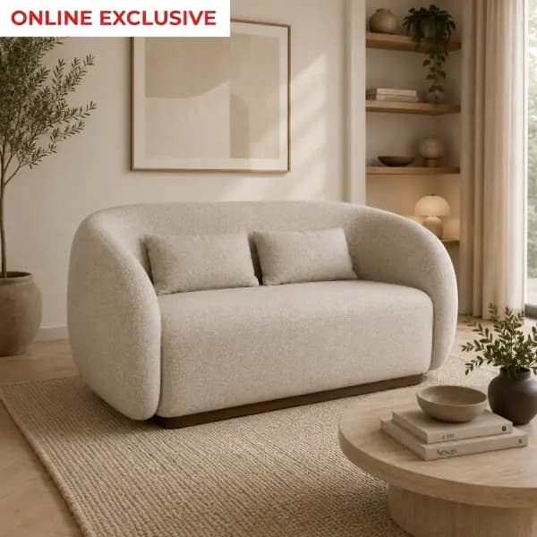 A contemporary two-seater loveseat featuring a distinct curvilinear silhouette with seamlessly rounded arms and backrest, upholstered in a light beige, textured bouclé fabric. The piece sits on a recessed, dark wooden plinth base, creating a floating effect. It includes two rectangular throw pillows matching the upholstery. — 3D model