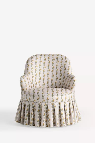 An upholstered armchair with a rounded back, rolled arms, and a pleated skirted base, covered in a cream fabric with a yellow and green botanical pattern. — 3D model