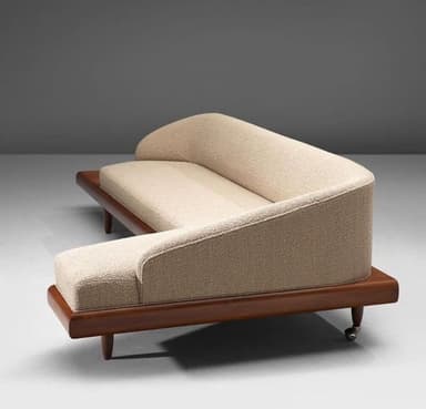 An L-shaped sectional sofa piece featuring a light-colored, textured upholstered seat and a gently curved backrest. It is set upon a dark stained wooden platform base, supported by tapered wooden legs, with some legs equipped with small casters. — 3D model