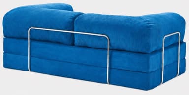 A vibrant blue modular floor sofa upholstered in corduroy fabric. The sofa features a multi-layered base, indicative of a convertible or modular design. It includes two cylindrical bolster cushions serving as backrests and a single bolster acting as an armrest, supported by a polished chrome metal frame on one side. The overall aesthetic is modern and casual. — 3D model