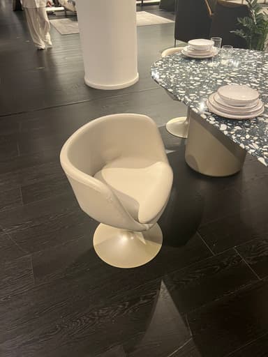 A modern accent chair with a rounded, upholstered seat and back, supported by a single, flared pedestal base. The chair has a low profile and appears to be designed for comfort and aesthetic appeal. — 3D model
