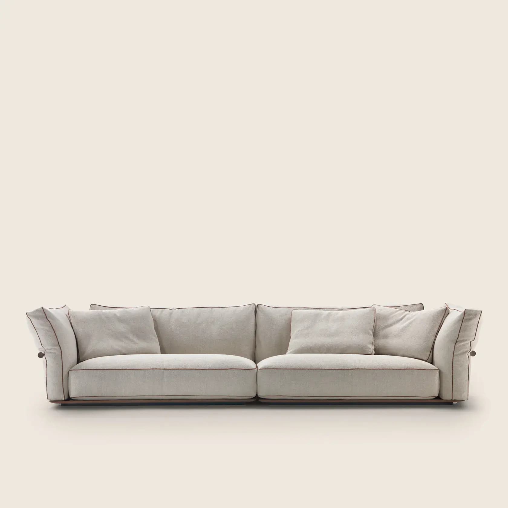 A modern upholstered sofa featuring a light, neutral fabric, dark contrast piping along all edges of the cushions and frame, and a low-profile silhouette with deep, plush seating. The armrests appear to be slightly articulated, possibly held by a side button detail. — 3D model