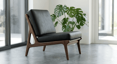 A contemporary lounge chair with a dark wood frame and black leather cushions, featuring an open, sculptural design. — 3D model