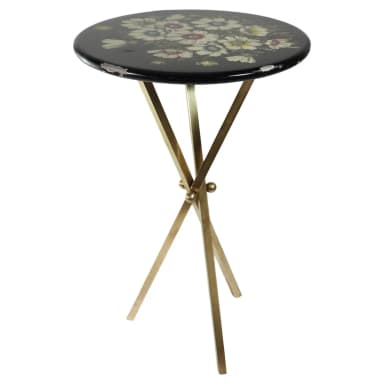 A small, round black table featuring a multi-color floral motif painted on its lacquered top, supported by a gold-toned metal X-frame base. The tabletop shows visible wear and chipping along its edges, revealing lighter material beneath the black finish. The base consists of four slender, straight legs, joined at the center in an X-shape. — 3D model