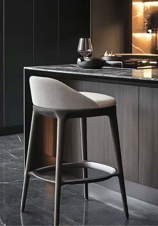 A contemporary bar stool featuring a light gray upholstered seat and a partially curved backrest, set upon a dark gray four-legged base with an integrated circular footrest. The design is sleek and minimalist, suitable for modern interiors. — 3D model