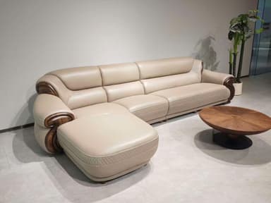 An L-shaped sectional sofa featuring cream-colored upholstery, likely leather or high-quality faux leather. The sofa is composed of multiple connected seating units, including an extended chaise lounge section. Distinctive dark, carved wooden elements are integrated into the armrests and along the base, providing a decorative contrast. The backrests and seat edges exhibit subtle quilted stitching patterns. — 3D model