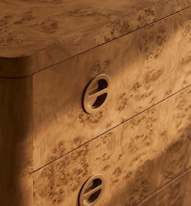 A three-drawer chest of drawers crafted with burl wood veneer, featuring rounded corners and edges, and circular recessed brass pull handles. The unit stands on integrated rounded feet. — 3D model