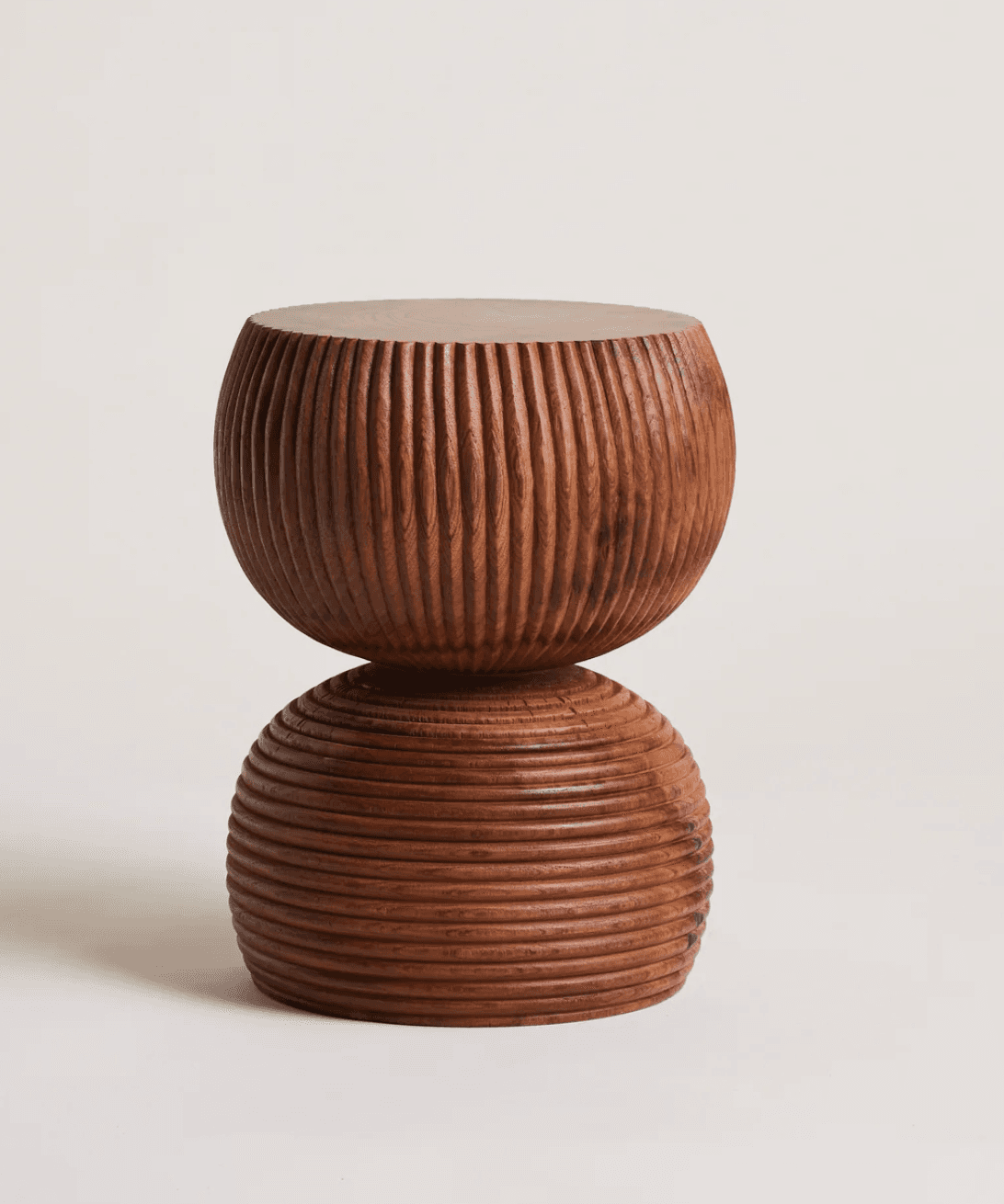 A sculptural accent table crafted from dark wood, featuring a stacked design of two rounded, intricately carved sections. The upper section displays vertical fluting, while the lower section exhibits horizontal ribbing, creating a contrasting textural effect. The piece has a flat top surface, suitable for holding items or serving as a small side table. — 3D model