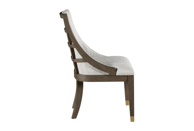 A side profile view of a dining chair. The chair features a dark-stained wooden frame with elegantly curved legs. The backrest is composed of vertical slats and is upholstered, as is the seat, in a light-colored, textured fabric. The front legs have decorative brass caps near the feet. — 3D model