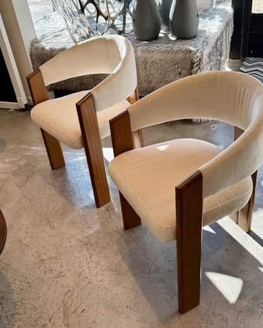 A contemporary armchair featuring a rounded upholstered back and seat, supported by a solid dark-stained wooden frame. — 3D model