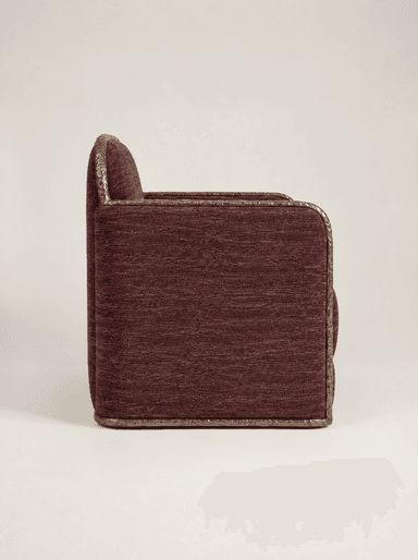 A contemporary upholstered armchair featuring a deep plum or burgundy textured fabric. It is characterized by a unique, decorative hammered metal frame that outlines the oval backrest, armrests, and base, providing a distinct stylistic element and material contrast. The seat cushion is integrated, presenting a substantial and refined form. — 3D model