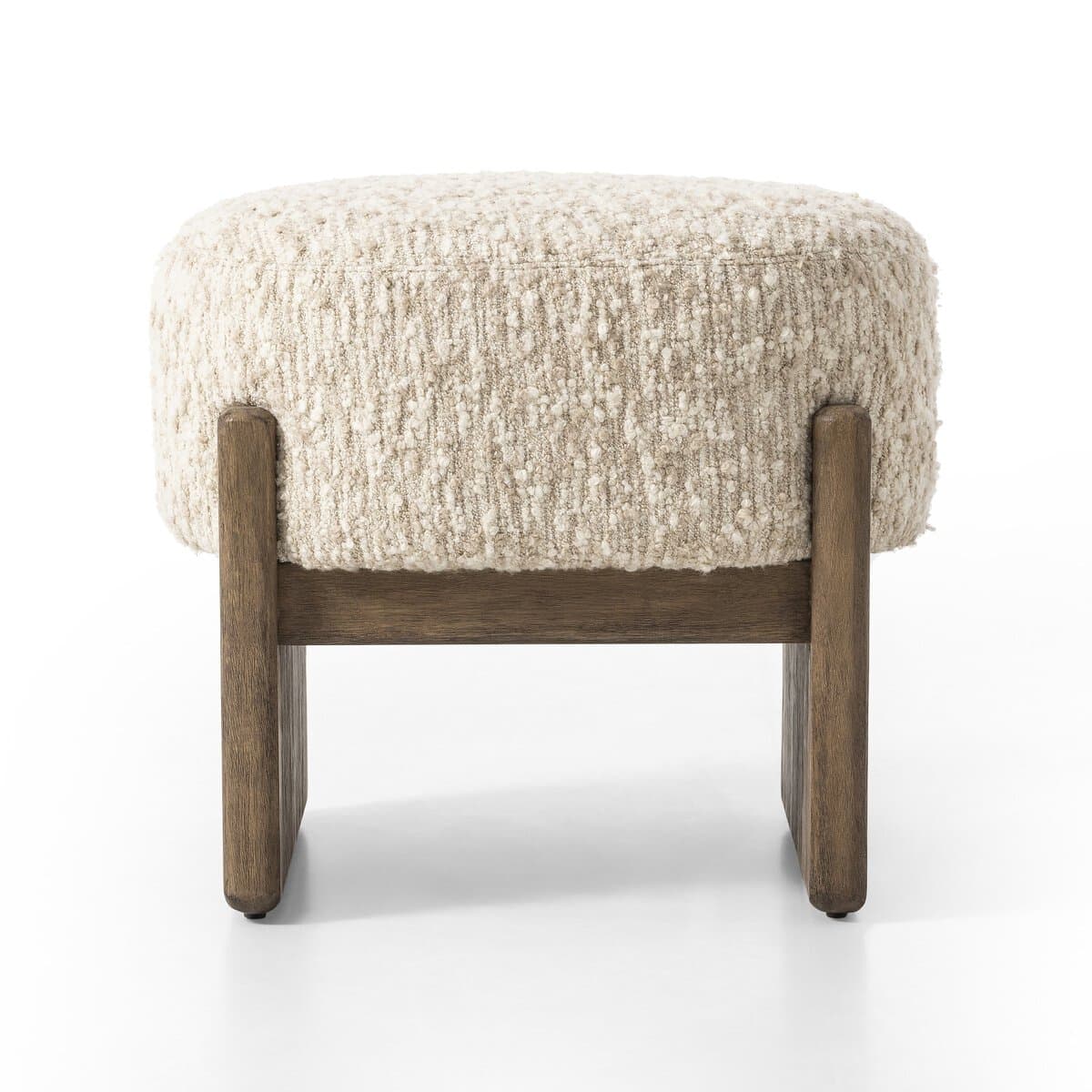 A rectangular ottoman with a textured, boucle-like upholstery in a neutral cream color. It is supported by a sturdy wooden base with two block-style legs at the front and two at the back, connected by a horizontal wooden beam. — 3D model