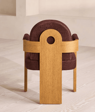 A modern armchair featuring a sturdy wooden frame and rich burgundy upholstery. The design incorporates solid, block-like wooden armrests and legs, with a gently curved, upholstered backrest and seat. The armrests also have padded cushions for added comfort. — 3D model