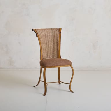 A vintage chair with a woven wicker back and a padded seat. The frame appears to be made of metal and is painted yellow with visible stitch-like detailing. The legs are curved and provide a decorative, elegant stance. The backrest has a distinctive shape, widening towards the top with curved accents. — 3D model