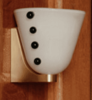 A modern wall sconce featuring a conical or bowl-shaped opal glass diffuser, illuminated from within. The diffuser is secured to a wall-mounted metallic base and wall with decorative dark-toned studs visible on its sides. — 3D model