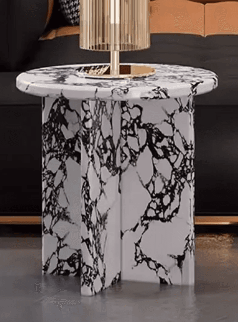 A round-topped end table with a base composed of three columnar supports with a marble-like pattern. A gold-toned lamp with a fluted shade is placed on top. — 3D model