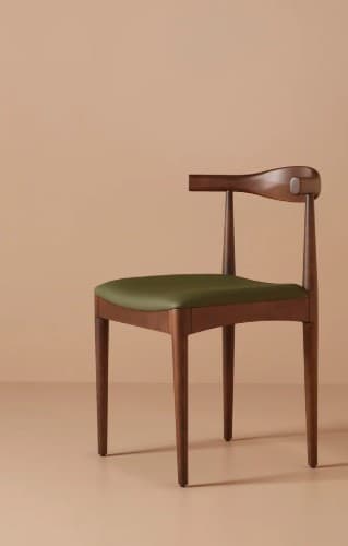 A wooden chair with a curved backrest that extends to armrests and a green upholstered seat. The chair has four tapered legs. The backrest features a subtle metallic accent piece on the right side. — 3D model