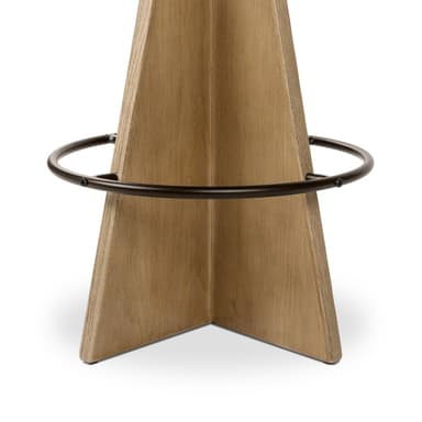 A contemporary bar stool with a tapered wooden base and a cushioned, upholstered seat. The base is constructed from light-colored wood with a distinct grain pattern and features a circular metal footrest. The seat is round, padded, and covered in a light-colored fabric, with a thin, contrasting trim around its edge. — 3D model