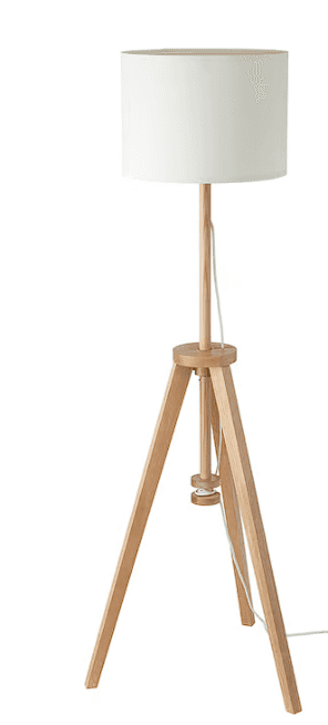 A floor lamp with a tripod base made of light-colored wood. The lamp has a cylindrical white fabric shade and a central wooden pole supporting the shade and the electrical components. — 3D model