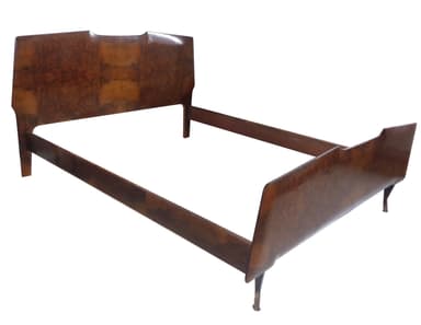 A wooden bed frame with a headboard and footboard. The headboard has a unique, undulating top edge and features a burl wood veneer. The side rails and footboard are made of solid wood with a darker finish. The frame rests on four short, tapered legs. The overall construction suggests it is an older piece of furniture. — 3D model