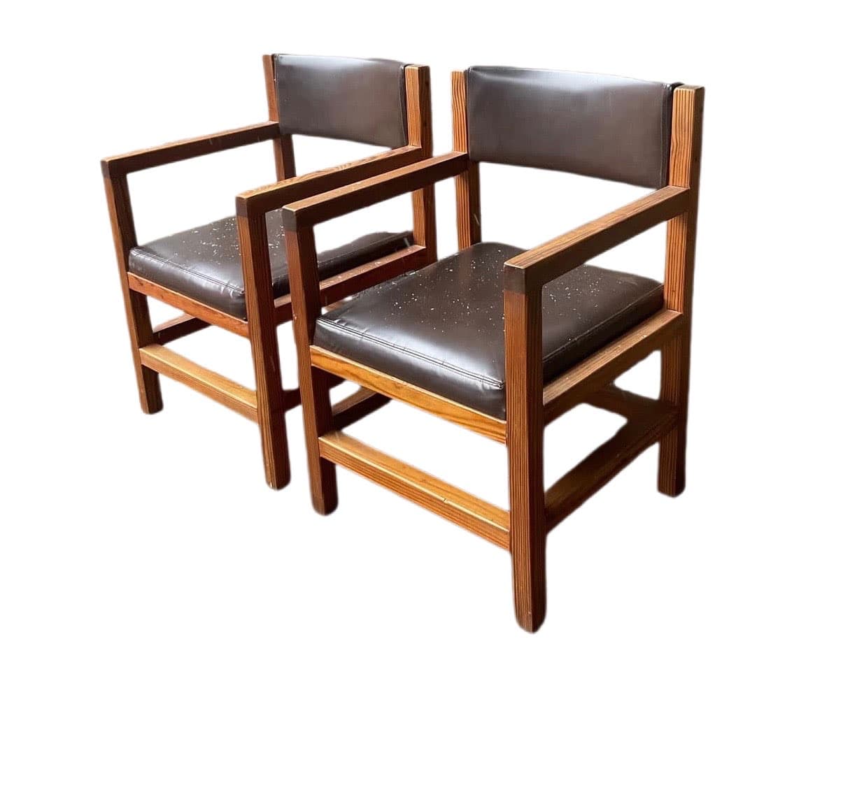 A wooden armchair with upholstered seat and backrest. The frame is constructed from solid wood beams, featuring a rectangular seat and back support. The armrests are formed by horizontal wooden beams connecting the front and back legs. The seat and back cushions appear to be covered in dark brown material, possibly leather or vinyl, with some visible flecks or dust on the seat cushion. The wooden frame has a natural finish, showcasing the grain of the wood. — 3D model