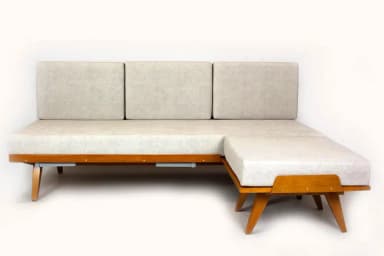 A Mid-Century Modern style daybed featuring a light-toned wooden frame and light grey fabric upholstery, accompanied by a matching, separate ottoman. — 3D model