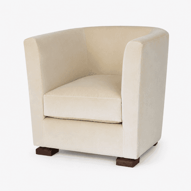 A contemporary club armchair, fully upholstered in a cream or light beige fabric, likely velvet or chenille. It features a rounded backrest that flows into integrated armrests, providing a cohesive and enclosed form. The seat cushion is separate and removable. The chair stands on four short, square block feet made of dark wood, providing a stable base and a subtle contrast to the light upholstery. — 3D model