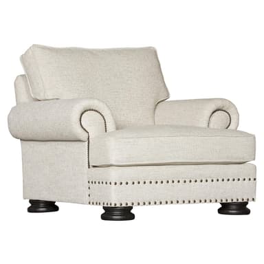 A single armchair upholstered in a textured light-colored fabric. It features rolled arms adorned with decorative nailhead trim, a plush seat cushion, and a supportive back cushion. The base of the chair is also upholstered and features a double row of nailhead trim, supported by four dark wooden bun feet. — 3D model