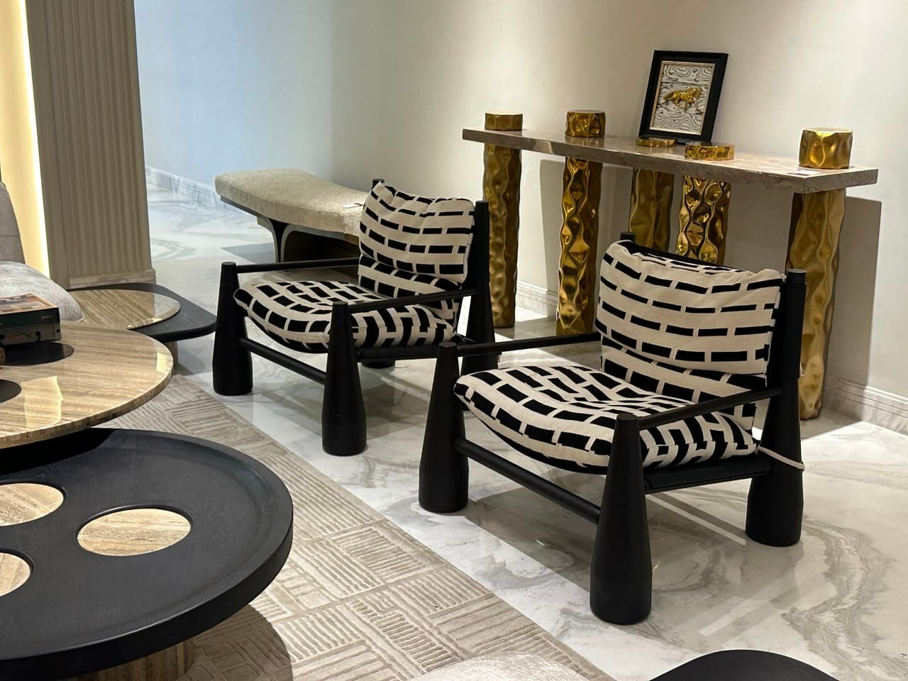 A contemporary armchair featuring a black lacquered wooden frame with sculptural, conical legs and armrest supports, fitted with two removable cushions upholstered in a high-contrast black and off-white geometric pattern. — 3D model