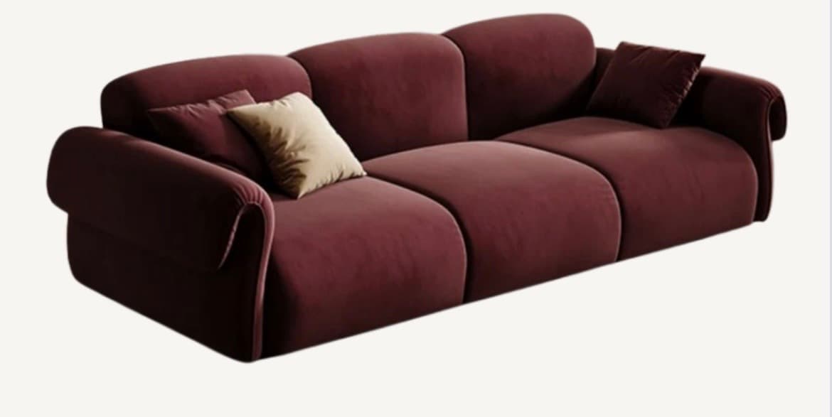 A contemporary three-seater sofa featuring a distinctive curved, segmented design, upholstered in a rich burgundy velvet fabric with prominent rolled armrests and loose throw pillows. — 3D model