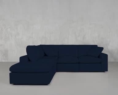 An L-shaped modular sectional sofa upholstered in a dark blue fabric. It features a chaise lounge component on one end, deep seating, plush back cushions, and includes several matching throw pillows. The design is contemporary, emphasizing comfort and versatility, suitable for various living spaces. — 3D model