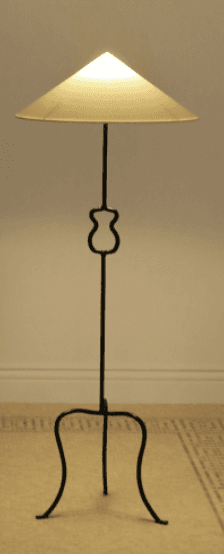 A tall, slender floor lamp featuring a black wrought iron (or similar dark metal) stand and a conical, off-white shade. The stem includes a distinctive curvilinear decorative element in its mid-section. The lamp is supported by a splayed, three-legged tripod base with curved feet. — 3D model