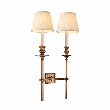 A traditional double-arm wall sconce featuring an antiqued brass finish and two pleated fabric shades. Each arm supports a candelabra-style light source, topped with an off-white, conical pleated shade. The central mounting plate is square with a decorative star motif. — 3D model