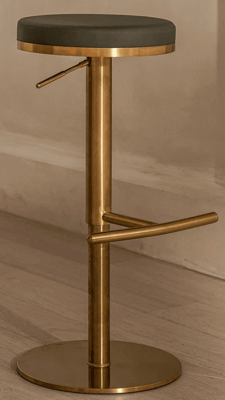 A modern adjustable bar stool featuring a round, dark grey upholstered seat and a polished brass finish on its metal components. The stool has a central cylindrical column for height adjustment, a curved circular footrest, and a sturdy flat disc base for stability. Its sleek design and material combination suggest a contemporary aesthetic. — 3D model