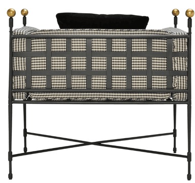 A bench with a dark metal frame and a cushioned seat upholstered in a black and white houndstooth pattern fabric. The backrest is also upholstered with the same fabric and features a grid-like design formed by dark straps. Two spherical finials are visible at the top of the backrest on the left side. — 3D model