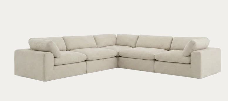 A light beige modular sectional sofa with an L-shaped configuration. It features deep, plush seating, loose back cushions, and wide, padded arms, giving it a relaxed and inviting aesthetic. The sofa is composed of multiple individual units that can be rearranged. — 3D model