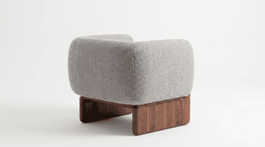 A contemporary armchair featuring a rounded, plush silhouette with light gray textured upholstery and an exposed solid dark wood frame forming the base and armrest accents. The chair has a minimalist yet inviting design. — 3D model