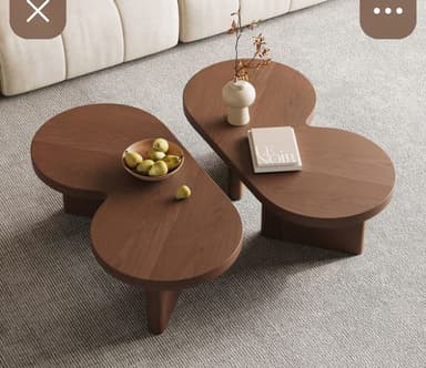 A modern coffee table with an organic, asymmetrical top and a minimalist base. The tabletop features a distinctive curvilinear shape, resembling two overlapping lobes. It is supported by two angled leg structures that are integrated into the overall design. — 3D model
