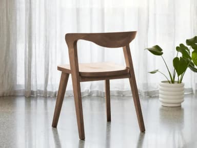 A modern dining chair constructed entirely from wood, featuring a curved backrest that flows seamlessly into the seat. The chair has four tapered legs, providing a sturdy base. The overall design is minimalist and organic. — 3D model