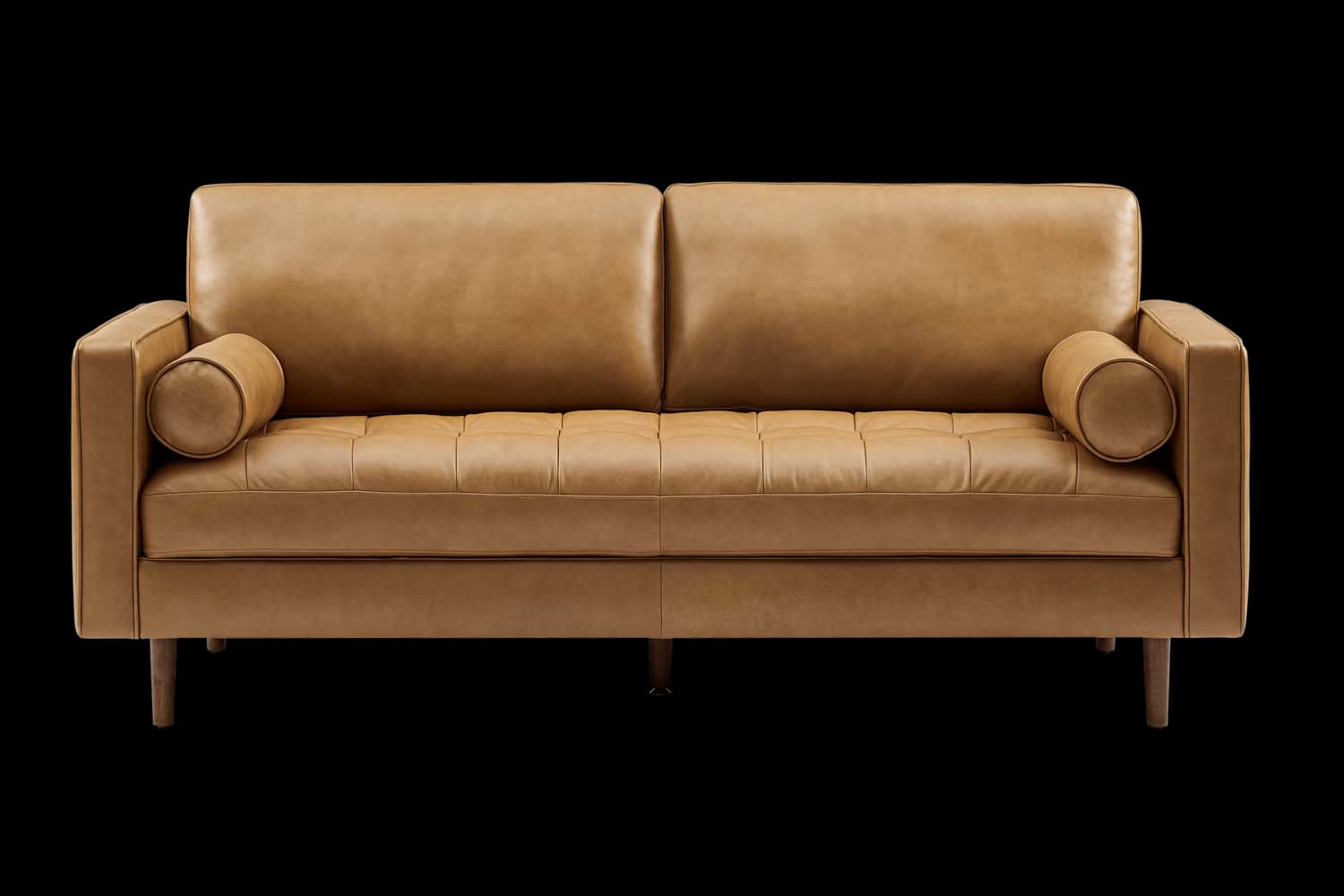 A modern three-seater sofa upholstered in tan or camel-colored leather. It features two large back cushions and two seat cushions with subtle square tufting. The arms are track-style, and it includes two round bolster pillows, one at each end. The sofa rests on four tapered, dark-colored wooden legs. — 3D model