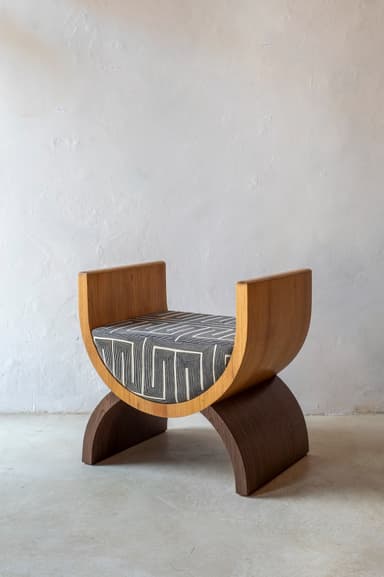 A modern stool with a curved wooden frame and a upholstered seat. The frame consists of two C-shaped wooden elements that support a central upholstered cushion. The backrest is formed by two upright, curved wooden pieces that extend upwards from the sides of the seat. — 3D model