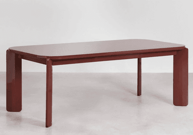 A close-up view of a table's corner and one leg. The table has a rectangular top with rounded corners and a thick, slightly beveled edge. The leg is solid and rectangular in cross-section, with a subtle taper towards the bottom and a rounded end. The design appears modern and minimalist. — 3D model