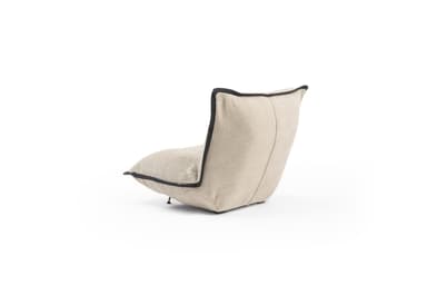 A low-profile armchair with a sculptural, continuous form, upholstered in a textured, light beige fabric with contrasting dark piping along the edges. The backrest is reclined, and the seat appears to be a single, soft cushion. Minimalist metal legs are visible at the base. The overall design is modern and organic. — 3D model