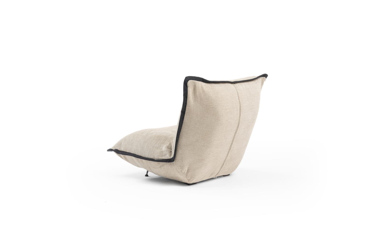 A low-profile armchair with a sculptural, continuous form, upholstered in a textured, light beige fabric with contrasting dark piping along the edges. The backrest is reclined, and the seat appears to be a single, soft cushion. Minimalist metal legs are visible at the base. The overall design is modern and organic. — 3D model