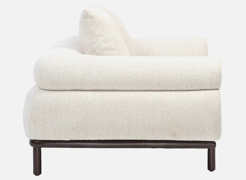 A side view of a contemporary sofa featuring thick, rounded, cream-colored boucle upholstery and a minimalist dark wood base with cylindrical legs. — 3D model