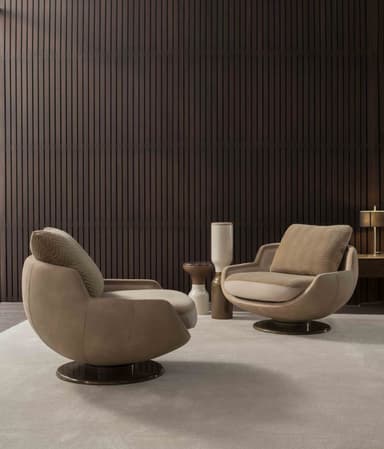 An upholstered swivel lounge chair featuring a deep, rounded form, integrated armrests, and a loose back cushion, all supported by a circular metal swivel base. — 3D model