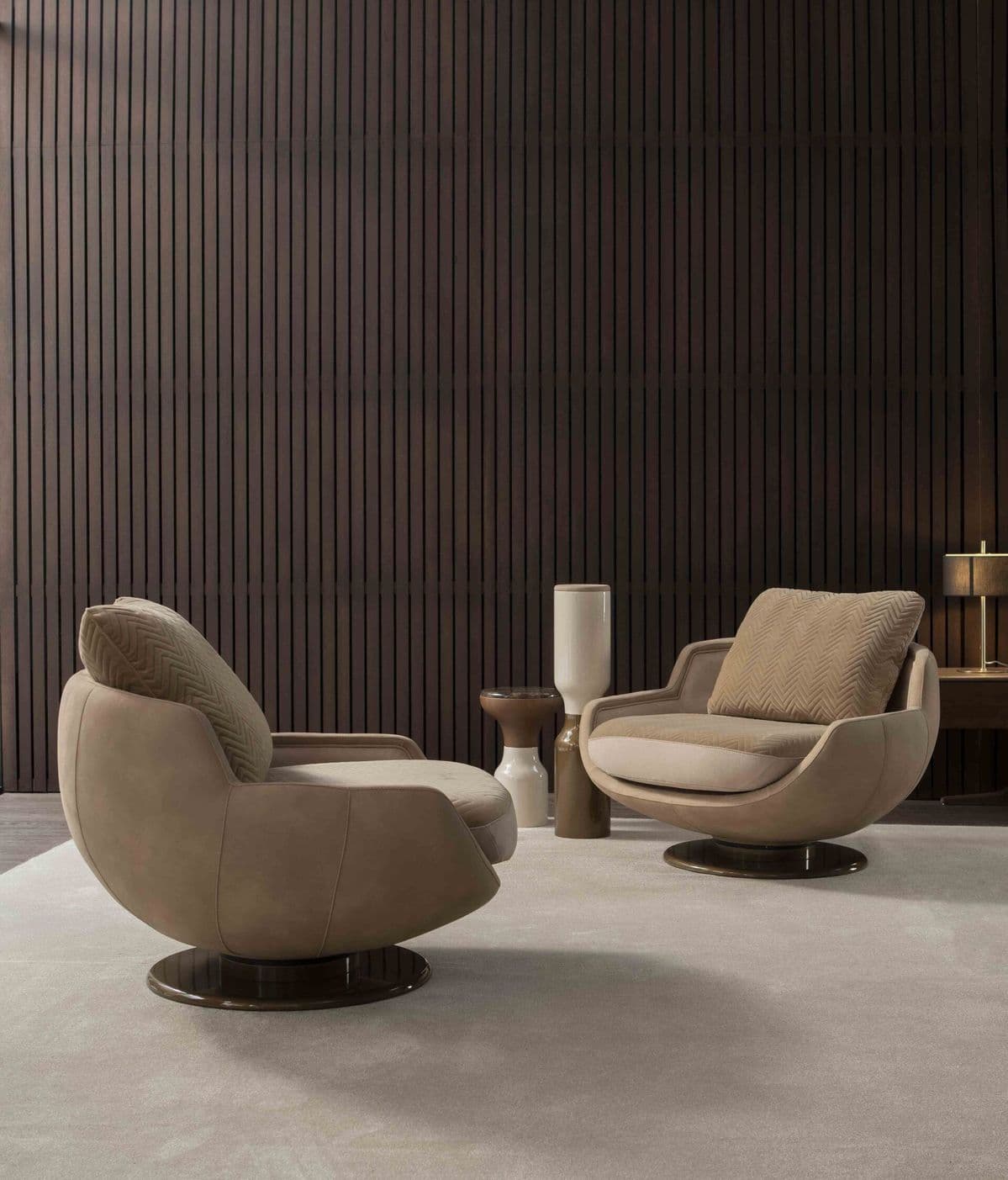 An upholstered swivel lounge chair featuring a deep, rounded form, integrated armrests, and a loose back cushion, all supported by a circular metal swivel base. — 3D model