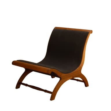 A low-profile X-frame lounge chair constructed from richly toned wood and upholstered in dark material. The frame features curved, intersecting legs that form an 'X' shape, connected by a turned stretcher bar at the back. The seat and backrest are simple, suspended panels of dark upholstery, providing a comfortable recline. The wooden frame has smooth, rounded edges, indicative of quality craftsmanship. — 3D model