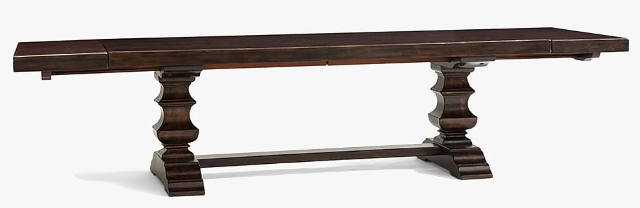 A dark brown, rectangular dining table with a thick, solid wood top. The table is supported by two substantial, turned pedestal legs connected by a stretcher. The legs have a classical, carved appearance with multiple bulbous sections and a stepped base. The finish is a deep, rich brown with visible wood grain, suggesting a traditional or rustic style. — 3D model