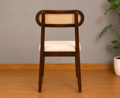 A contemporary dining chair featuring a dark stained wooden frame, a distinctive oval-shaped backrest with natural cane webbing, and a light beige upholstered seat. The chair's tapered legs are accented with brass ferrules on the front two feet. — 3D model
